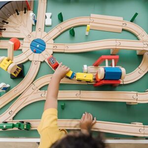 A child is playing with a train on a wooden track