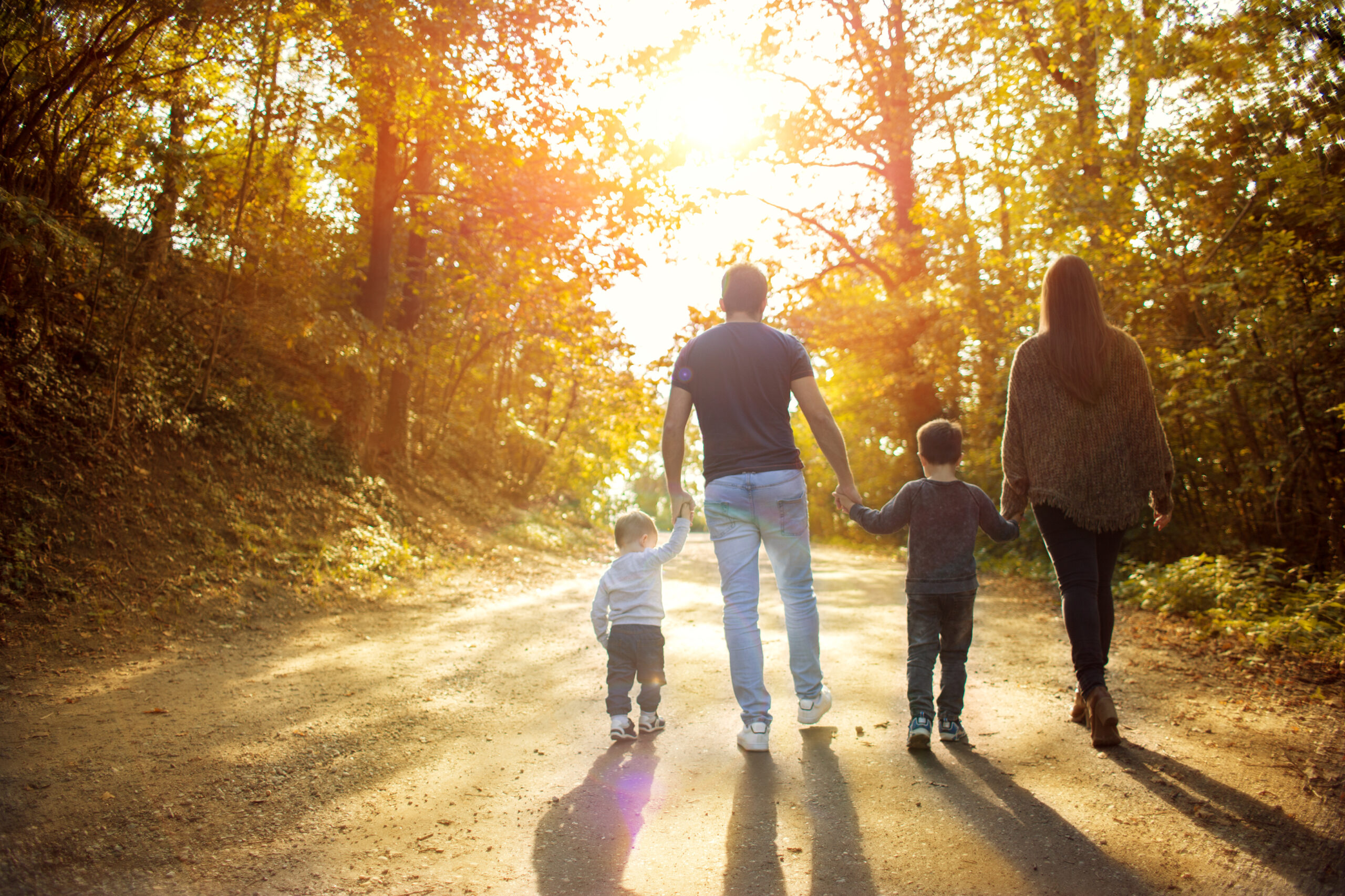 A family of four hikes in a forest in the fall.