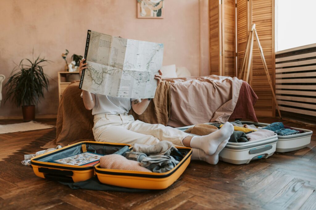 Woman looking at world map with travel luggage
