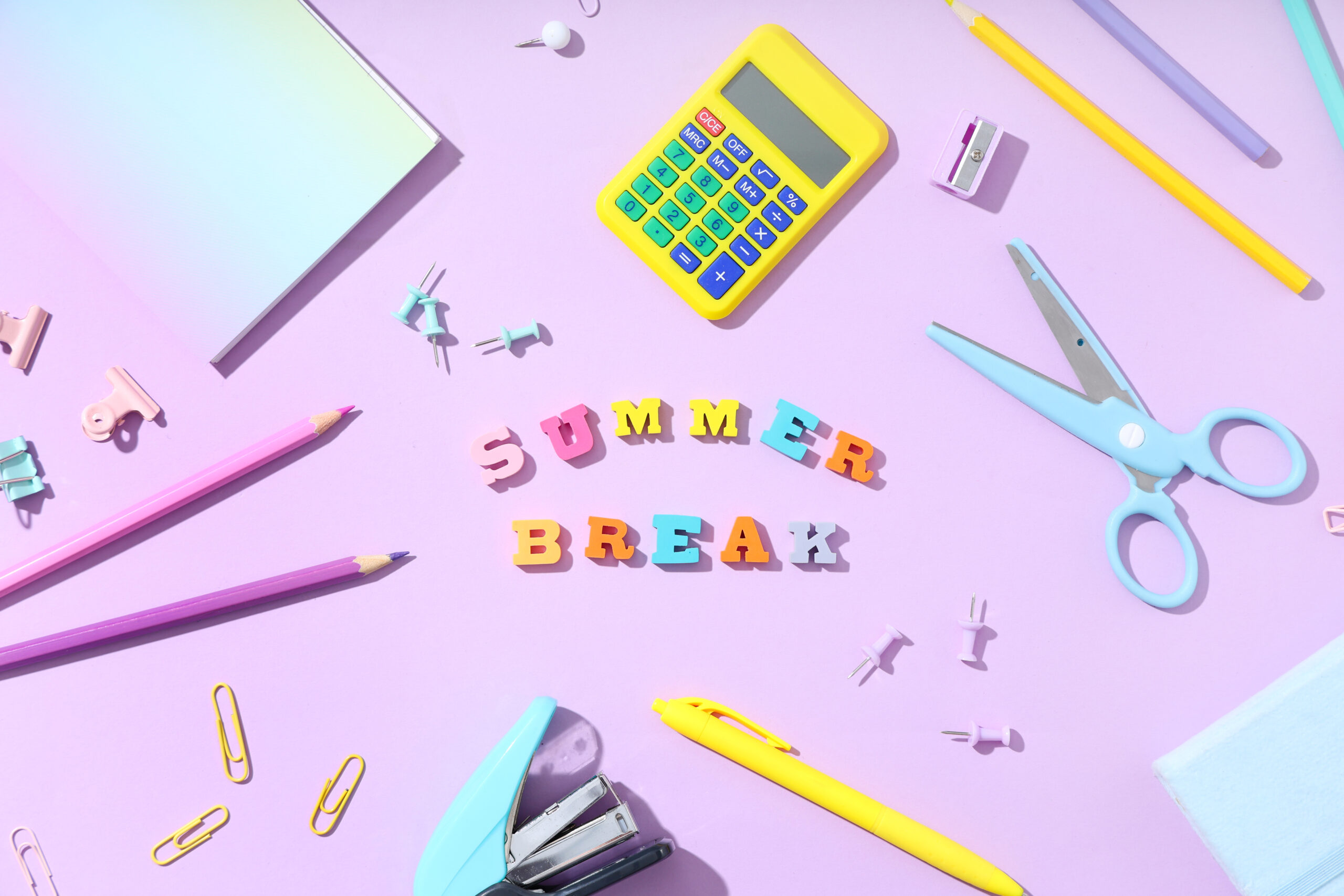 'Summer Break' is spelled out with block letters and surrounding it are various tools like scissors, calculators, colored pencils, and staplers.