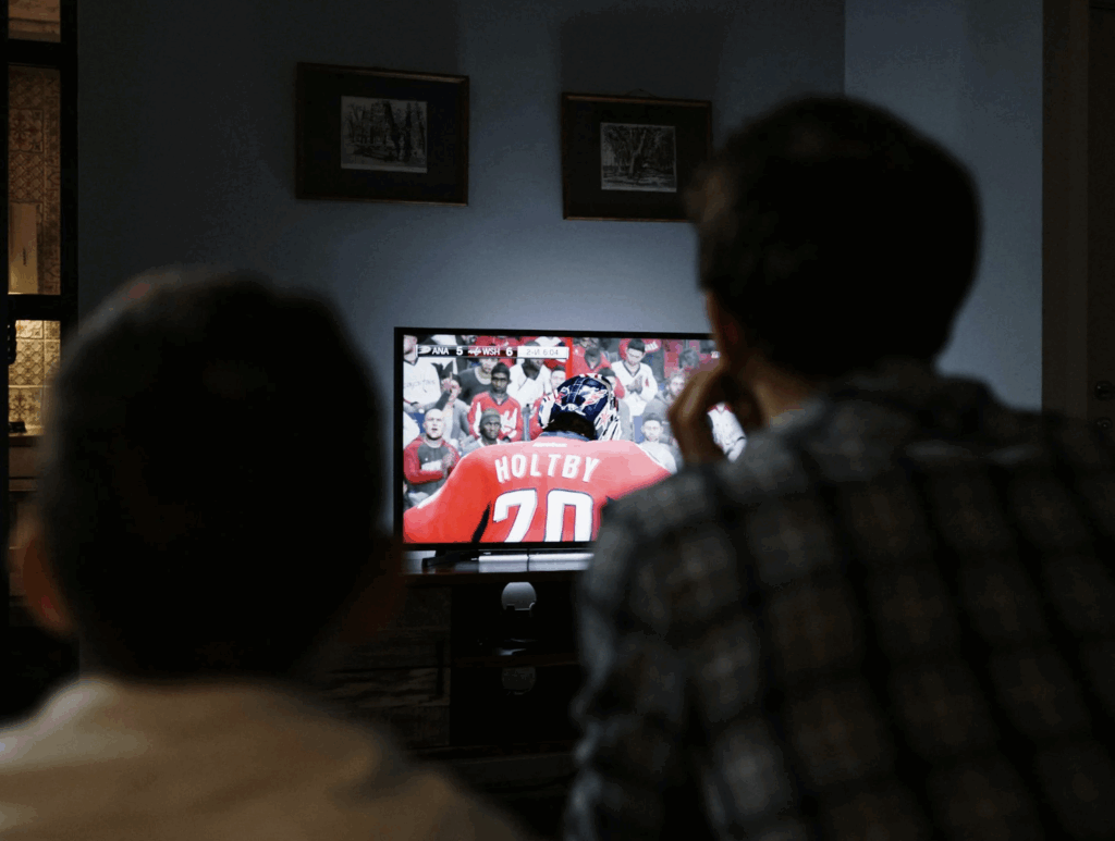 Father and son watching live hockey on ESPN with the Disney+, Hulu, ESPN Unlimited streaming bundle.