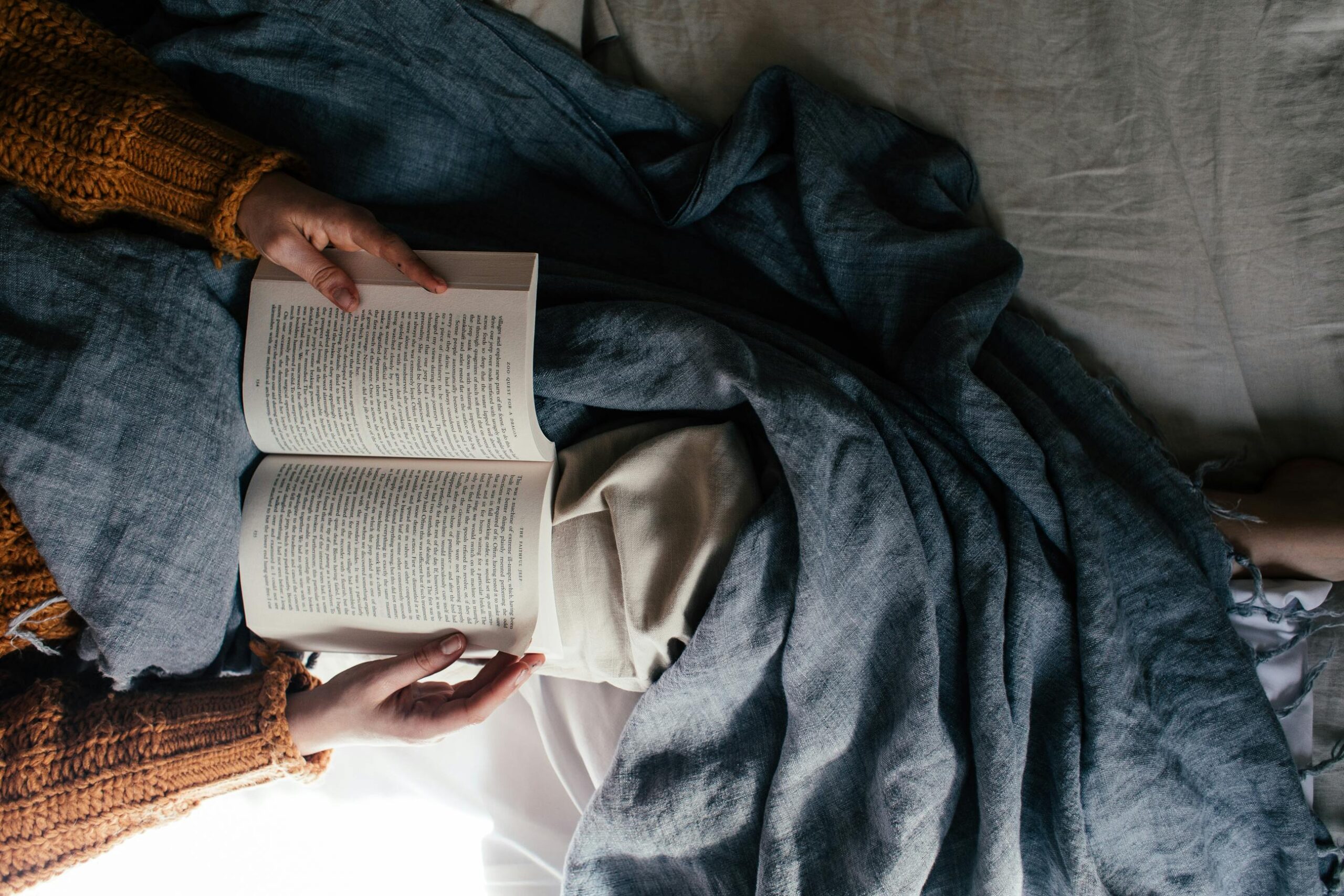Woman reading a book with a blue blanket