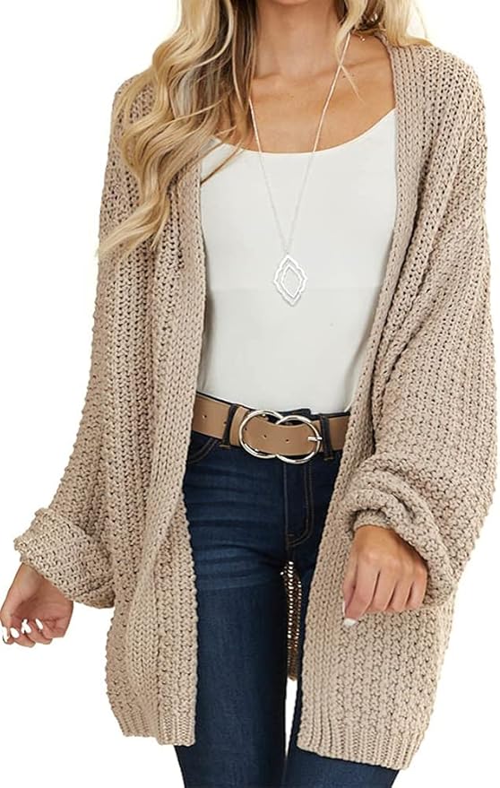 Woman in a beige oversized knitted cardigan, white top, and stylish belt, showcasing a casual, trendy look.