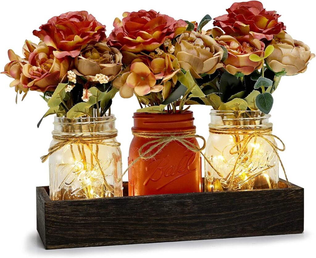 Mason Jar Center Piece with Faux Autumn Flowers and Fairy Lights inside. Mason Jars are sitting inside a farmhouse rustic style wooden box.
