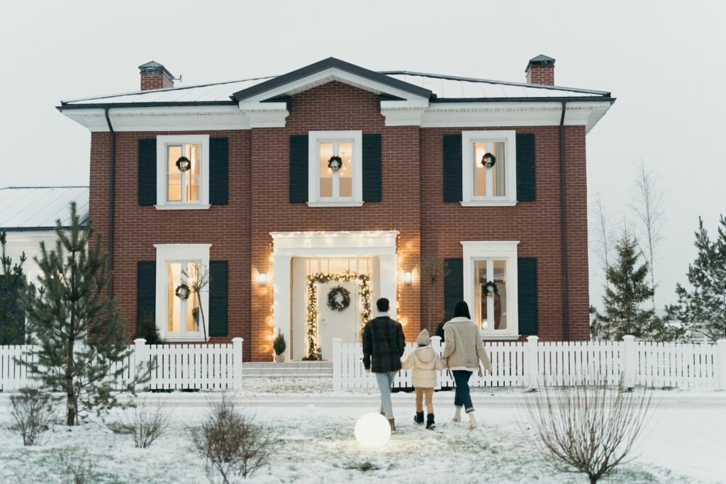 Family walking toward front porch, decorated for the winter holidays.