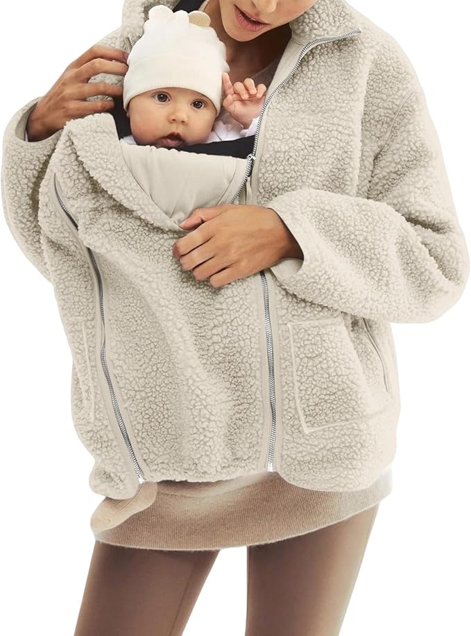 A mother wearing a fleece jacket with her baby in the carrier pocket