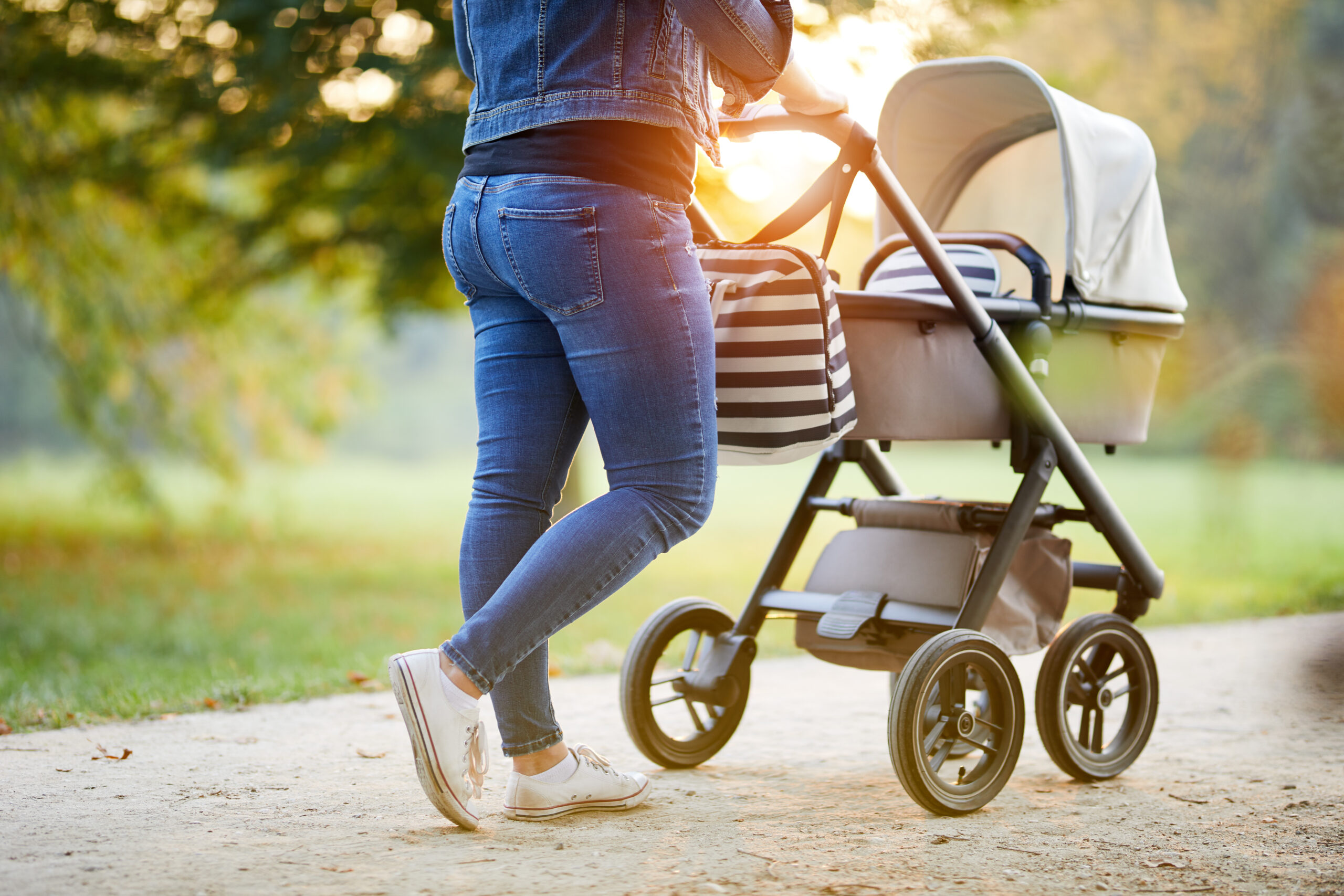 A woman pushes her child in a stroller during sunset