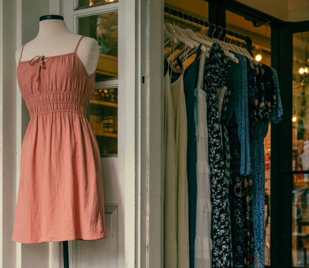 Spring outfits on racks at a store front.