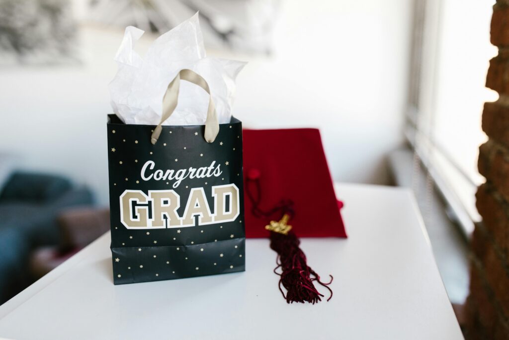 Graduation gift on table next to maroon graduation cap.