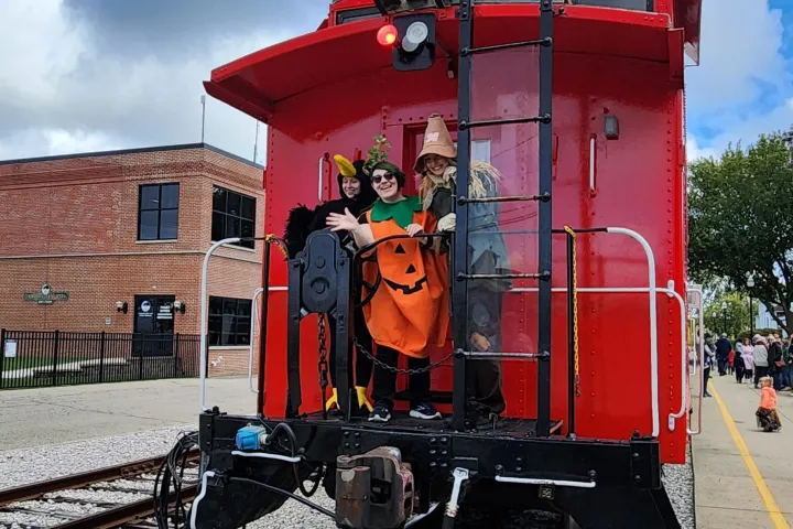 Costumed characters riding the red caboose of the Coopersville Pumpkin Train