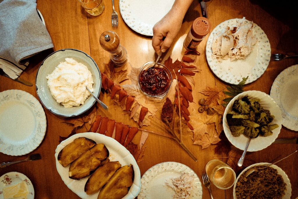 Friendsgiving appetizer spread featuring roasted vegetables, sliced turkey, dips, and seasonal fall table decor.