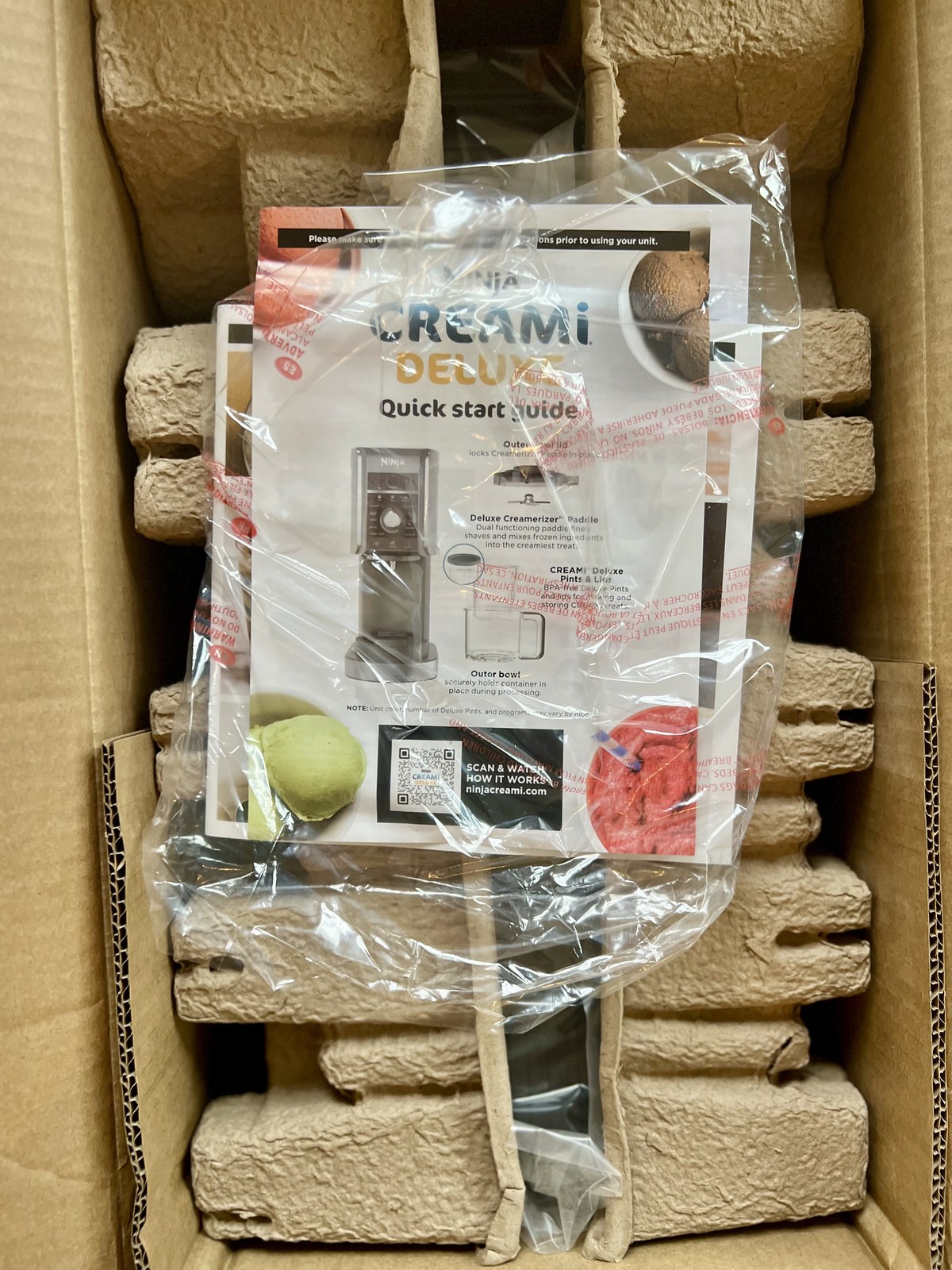 Ninja CREAMi Deluxe on a kitchen counter with its pints, lids and recipe booklet