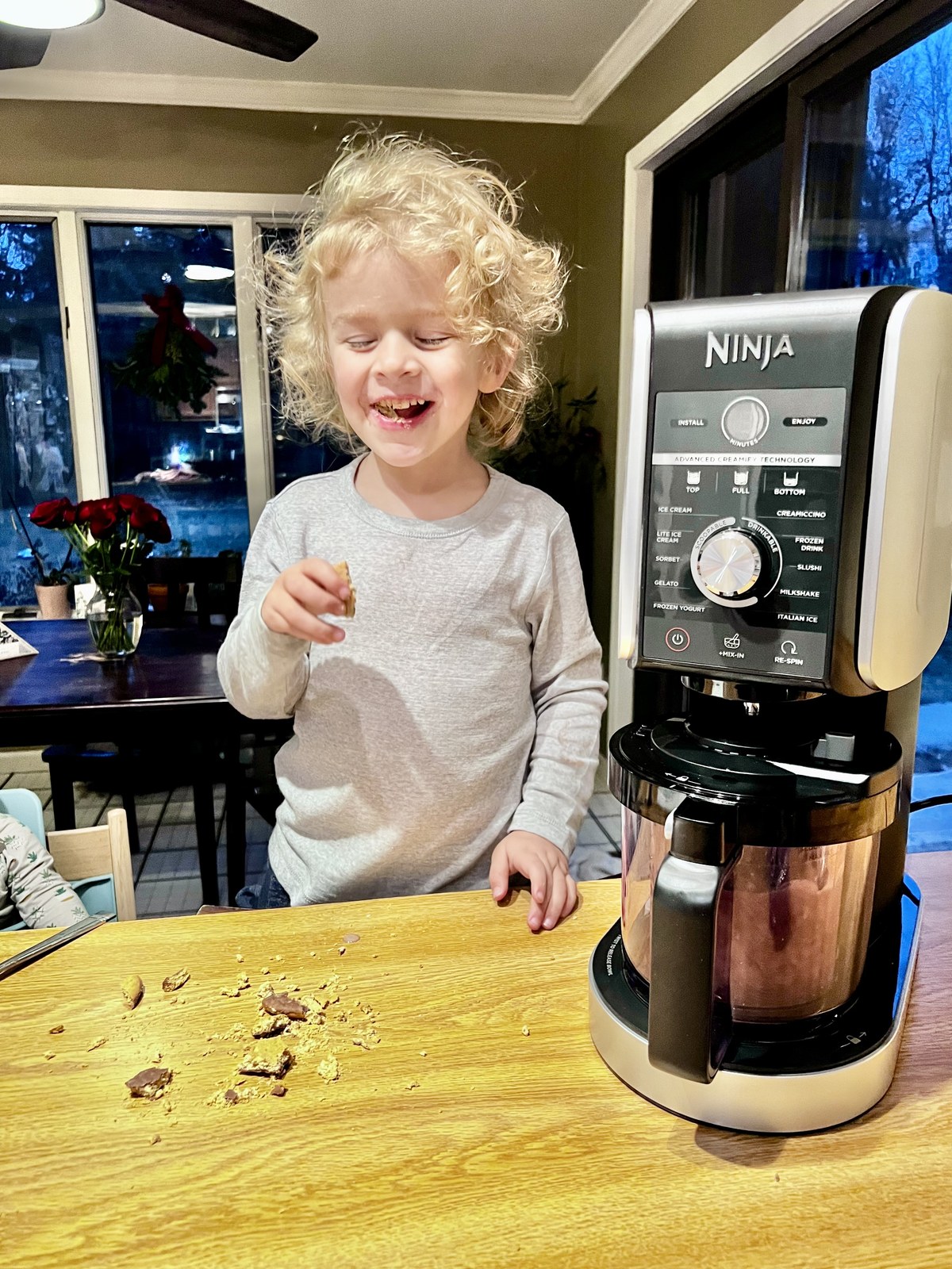 Child standing beside a Ninja CREAMi Deluxe part-way through making a batch