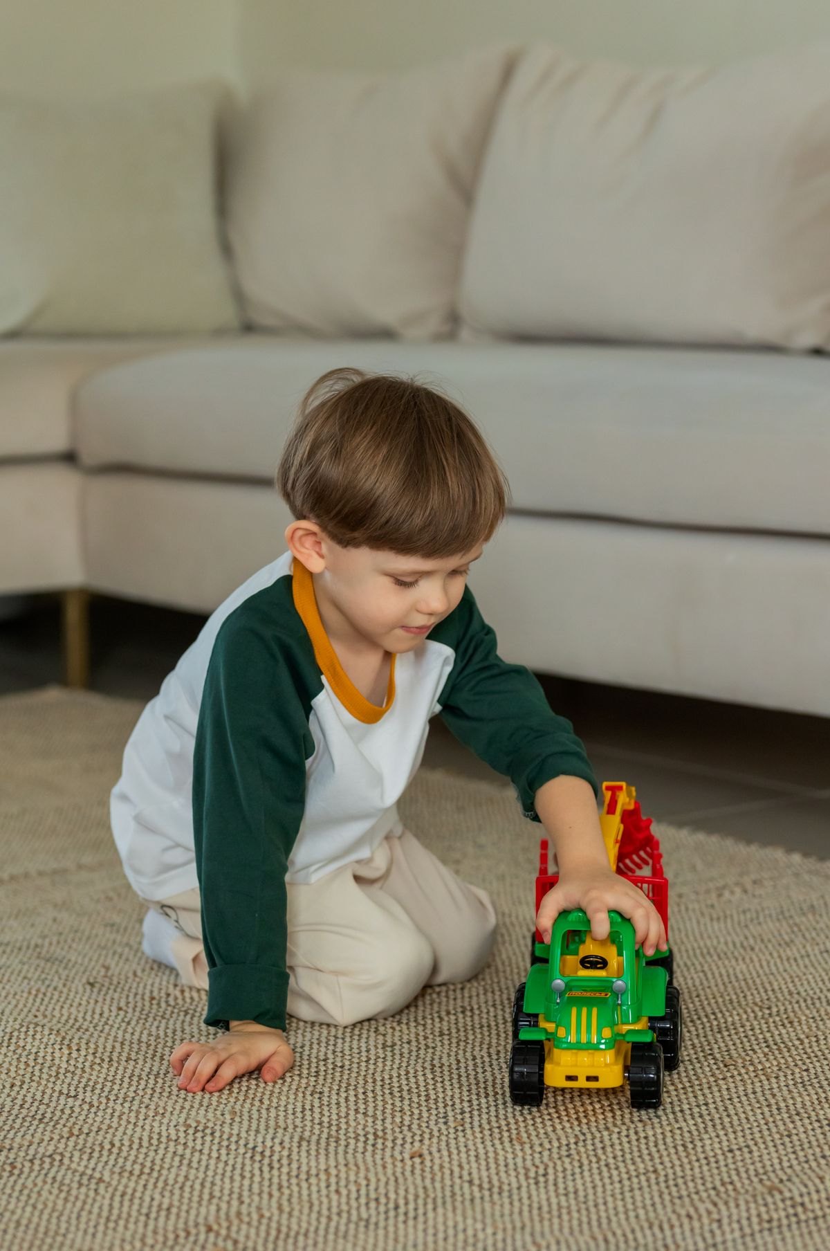 Boy playing with a toy tractor on the living room rug
