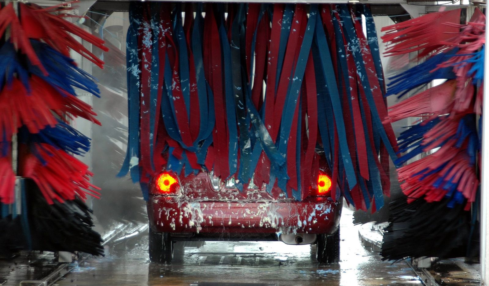 Car moving through red and blue car wash brushes