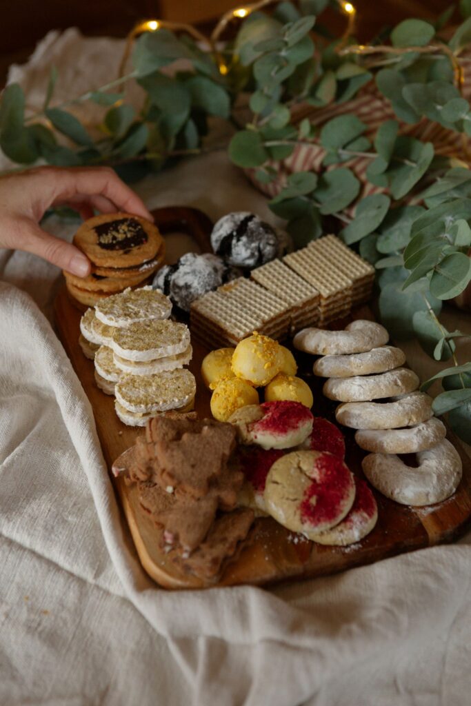 A finished Christmas cookie tray with an assortment of cookies and greenery