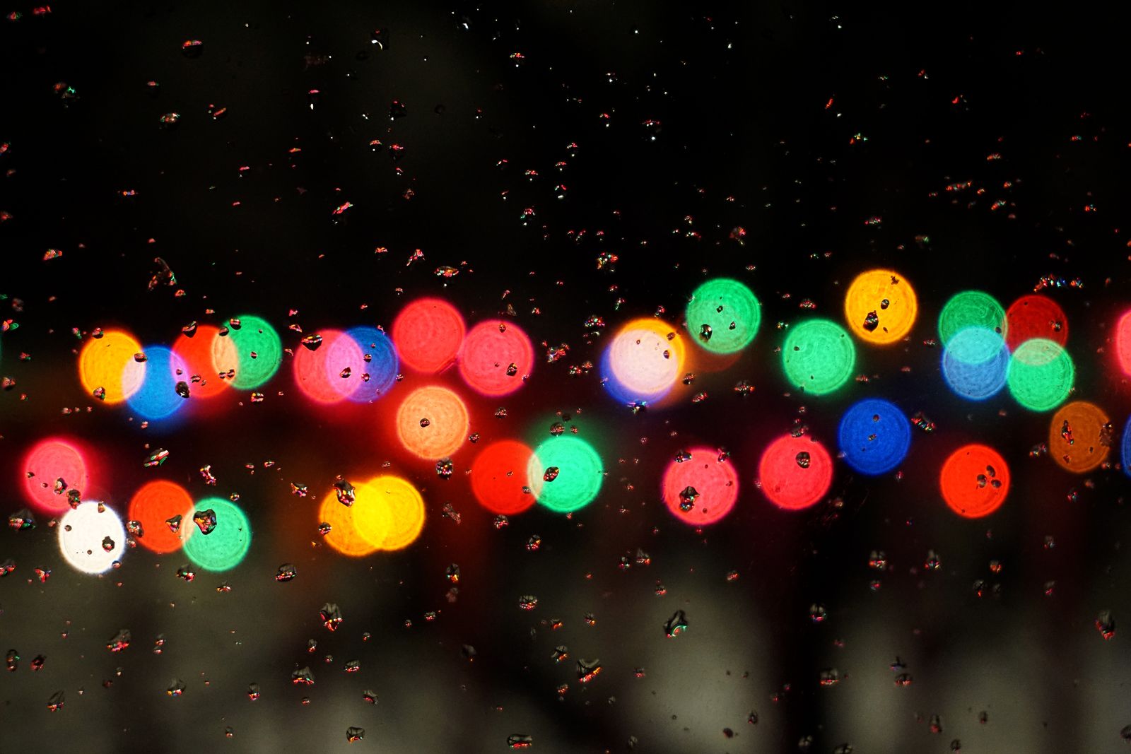 Blurry colorful Christmas lights seen through a car window at night