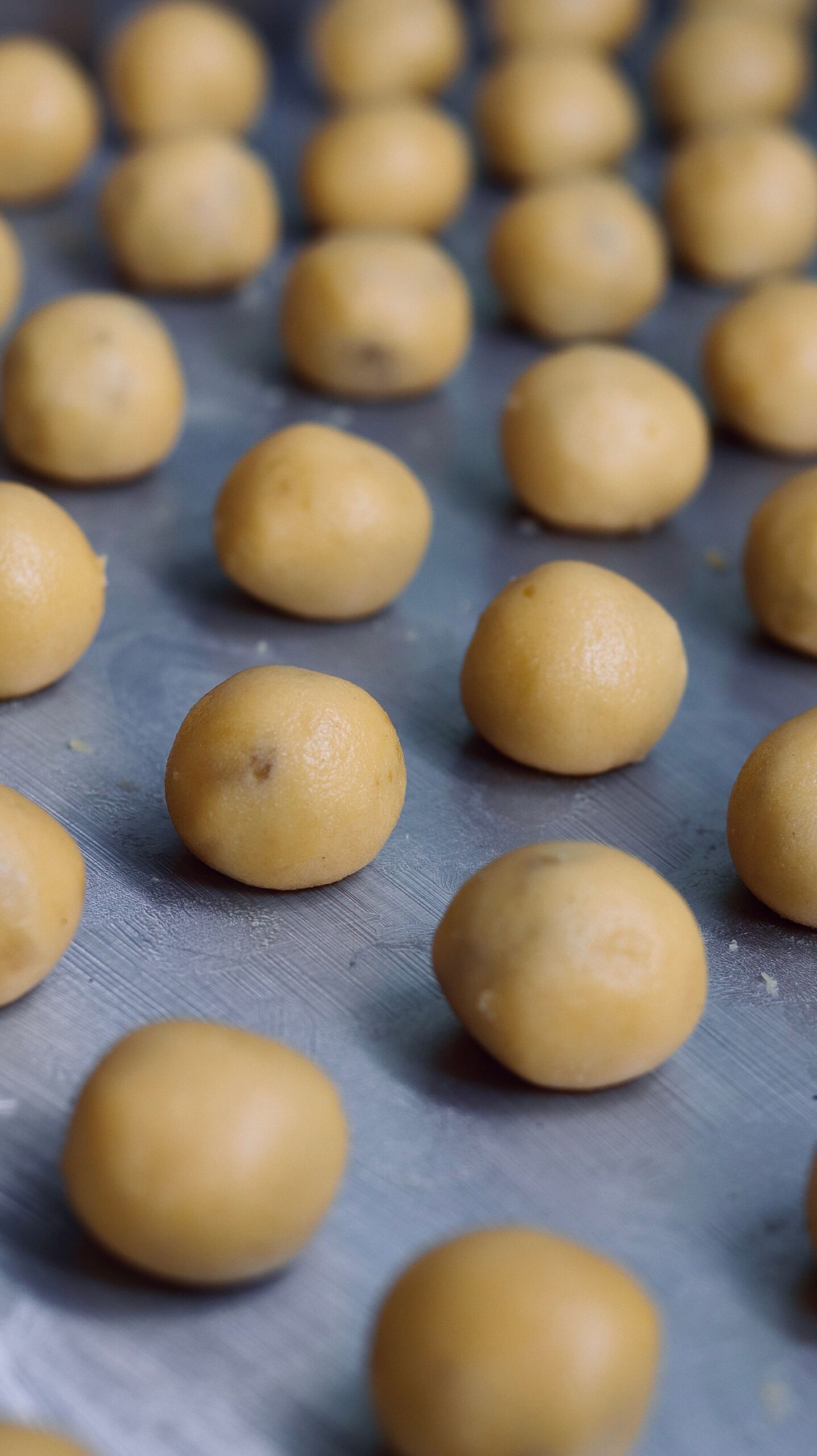 Rows of portioned cookie dough balls on a sheet pan ready to freeze