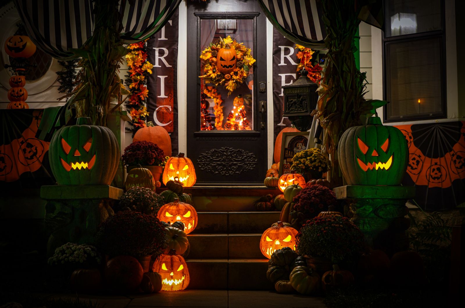 Halloween decorated front porch with lit jack-o-lanterns on the steps