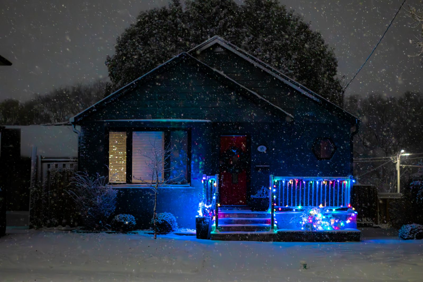 A house covered in colorful Christmas lights on a snowy night