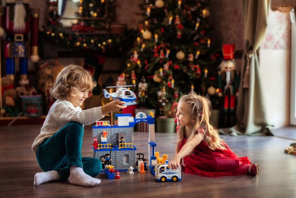Kids playing with toys in front of a Christmas tree