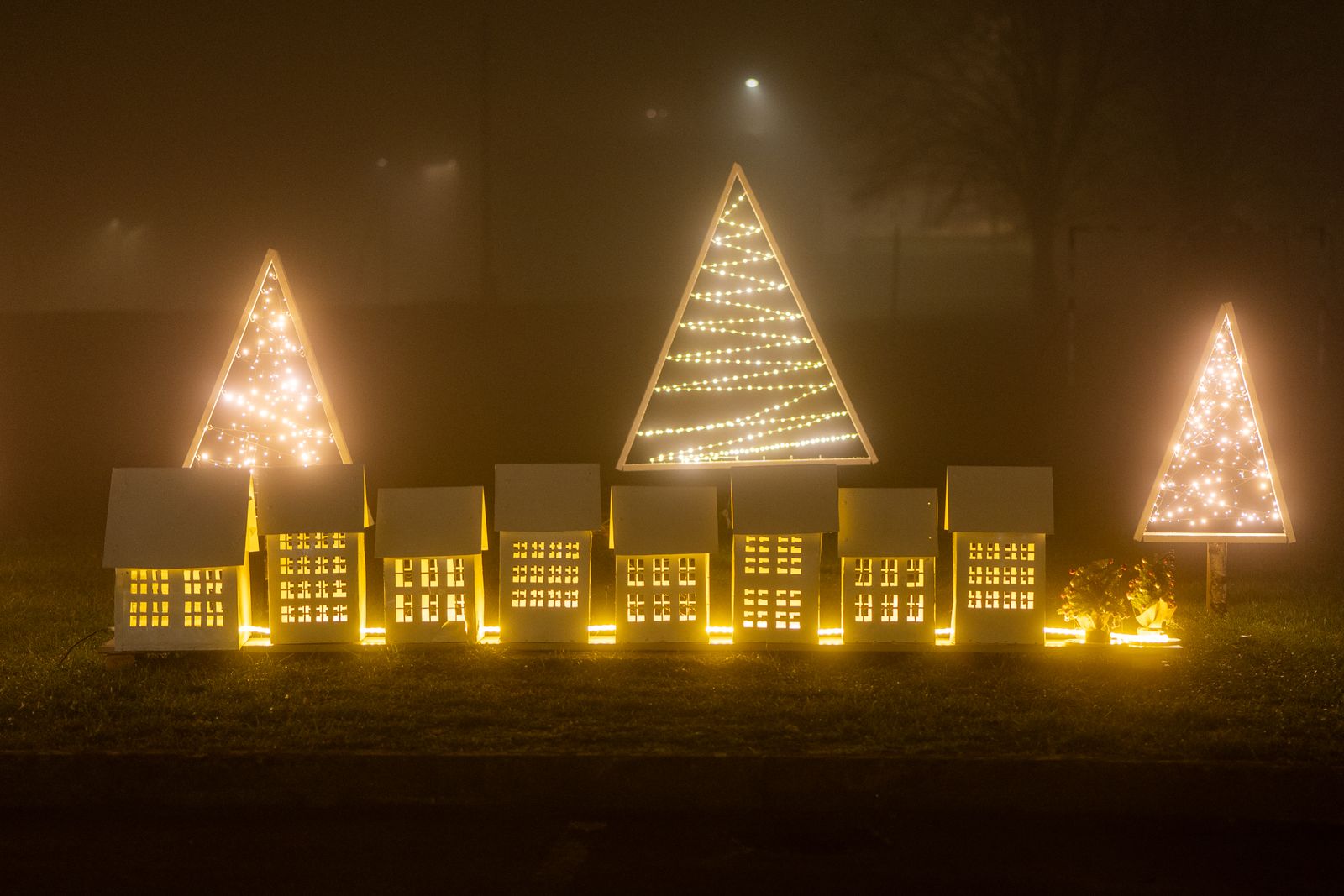 Glowing light-up trees and little houses in a dark yard display
