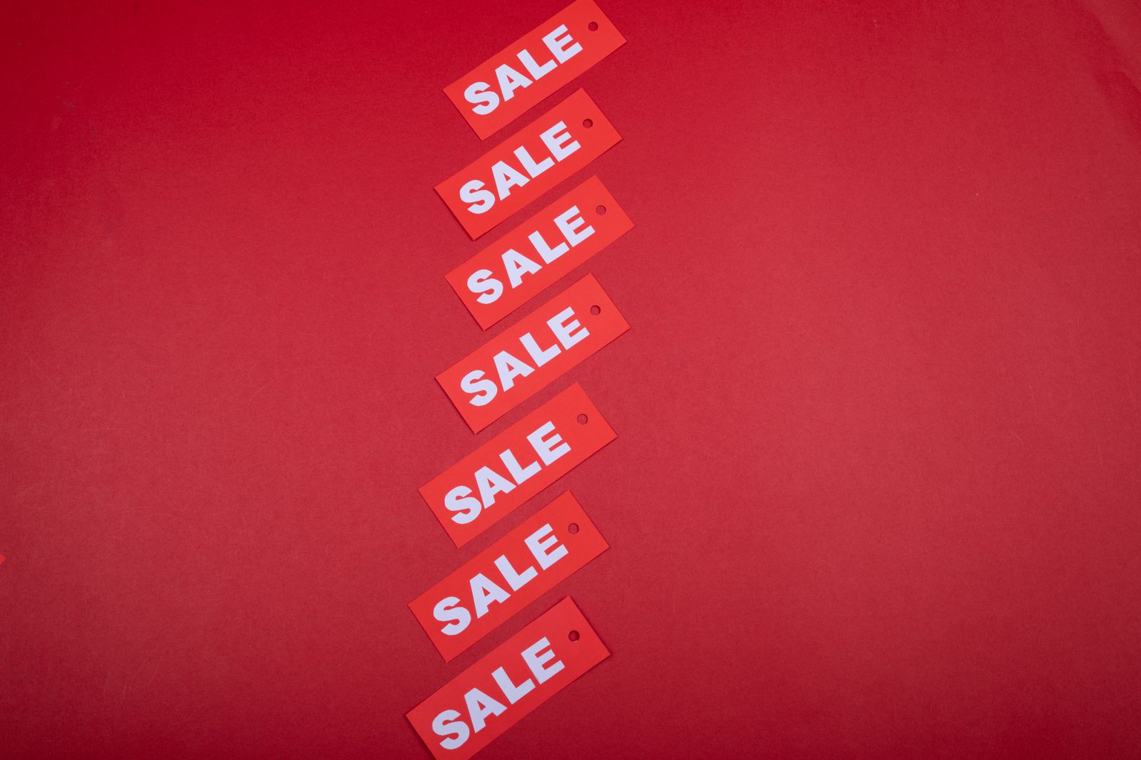 A diagonal row of red sale tags on a red background