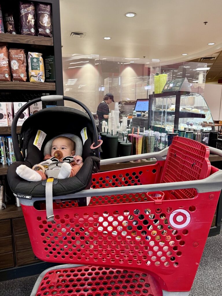 Baby in a car seat riding in a red cart while shopping Target Black Friday deals