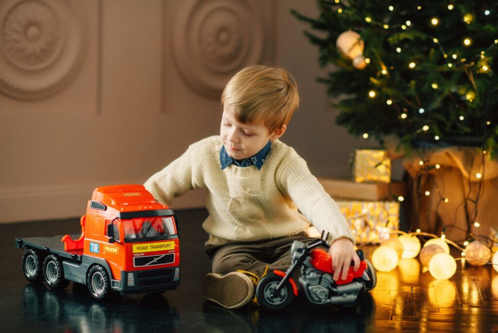 Little boy playing with a toy truck by the Christmas tree