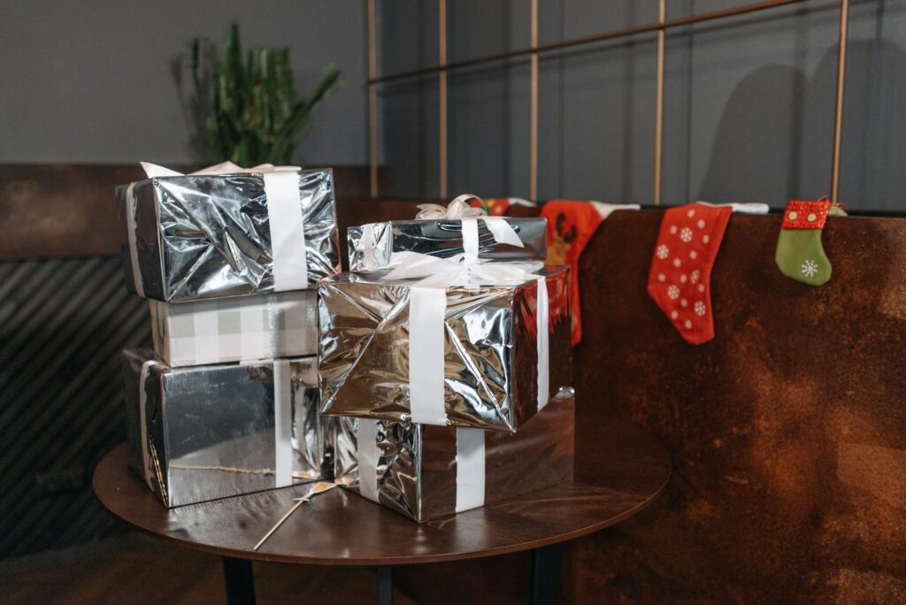 Wrapped silver gifts next to Christmas stockings